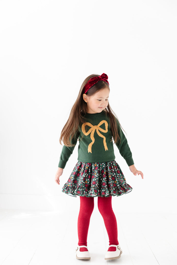 little girl wearing matching christmas outfit set with bow sweater and christmas floral dress