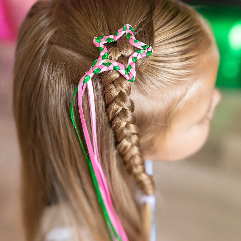 little girl with pink and green braided ribbon hair clip in star shape with ribbon streamers