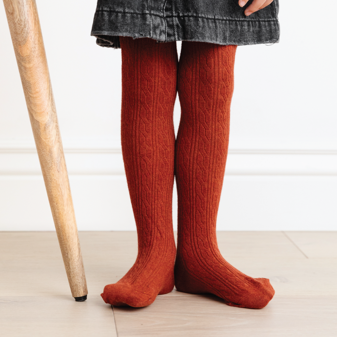 girl wearing brick red cable knit tights and black denim jumper