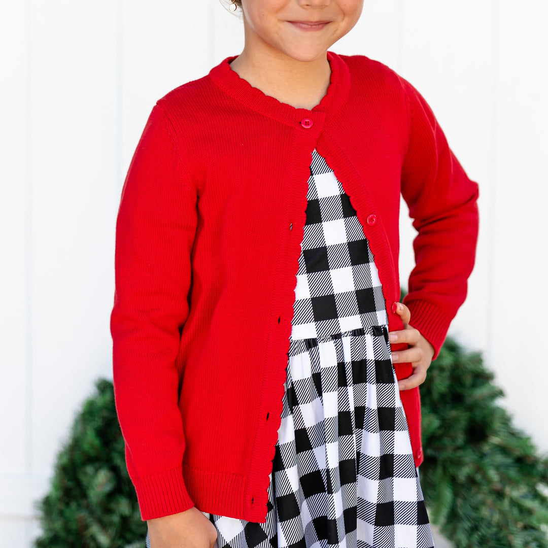 detail shot of girls bright red Christmas Cardigan paired with buffalo plaid twirl dress