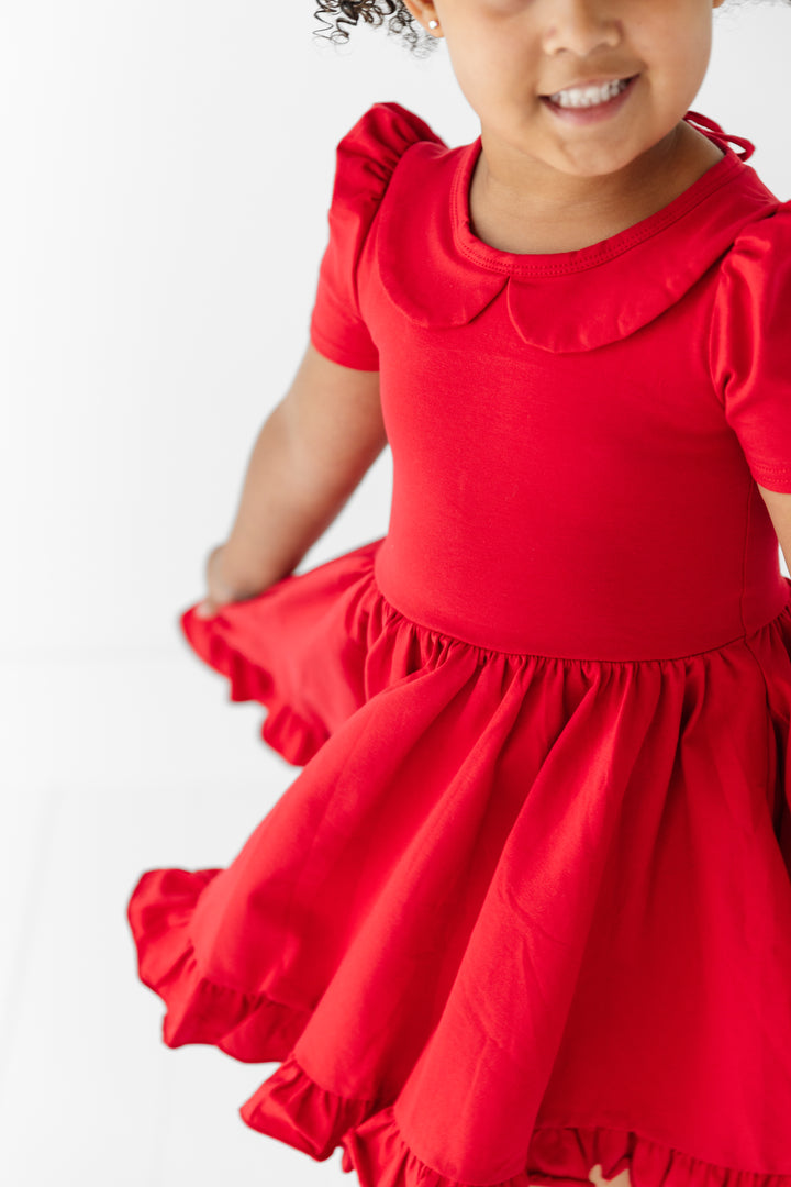 detail of little girl in bright red cotton blend twirl dress with short puffed sleeves, ruffle hem and collar for back to school and christmas