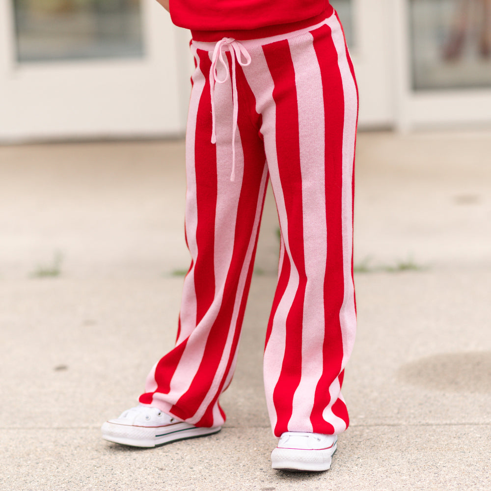 girl in bright red and light pink striped cotton knit sweater pants and matching red sweater paired with white sneakers