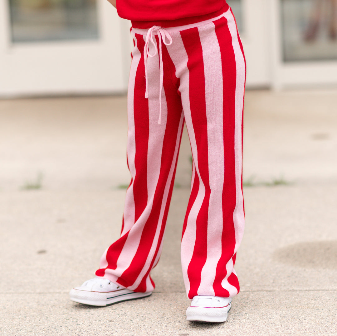 girl in bright red and light pink striped cotton knit sweater pants and matching red sweater paired with white sneakers