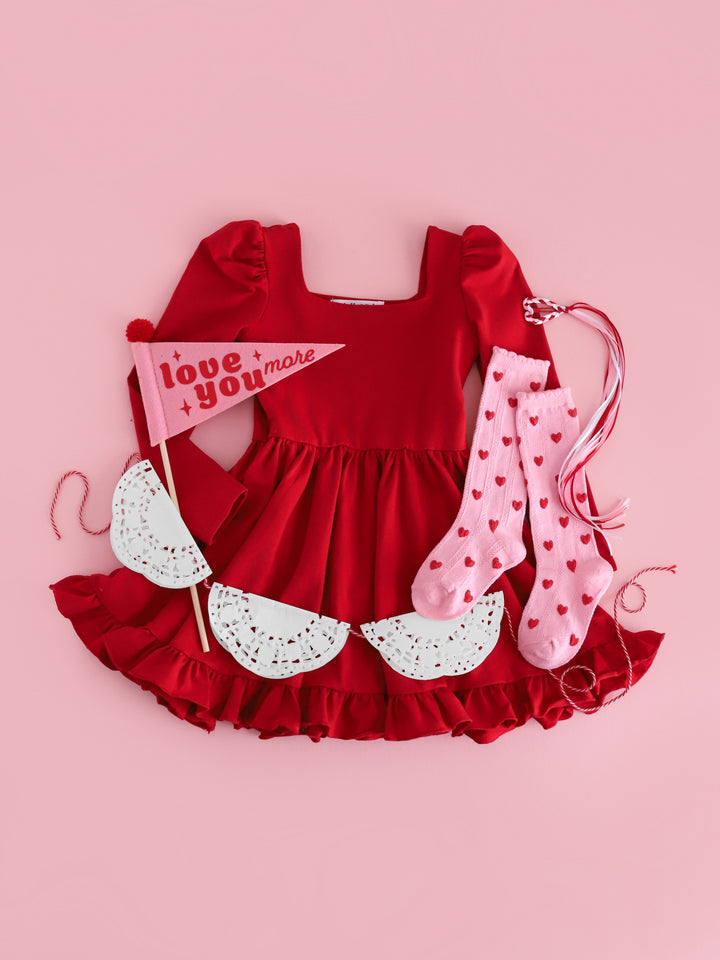 girls' bright red long sleeve dress paired with pink knee high socks with red embroidered hearts and heart shaped hair clip with ribbon streamers