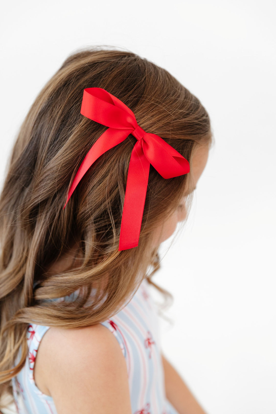 little girl wearing red satin bow on clip to match 4th of July bow print twirl dress