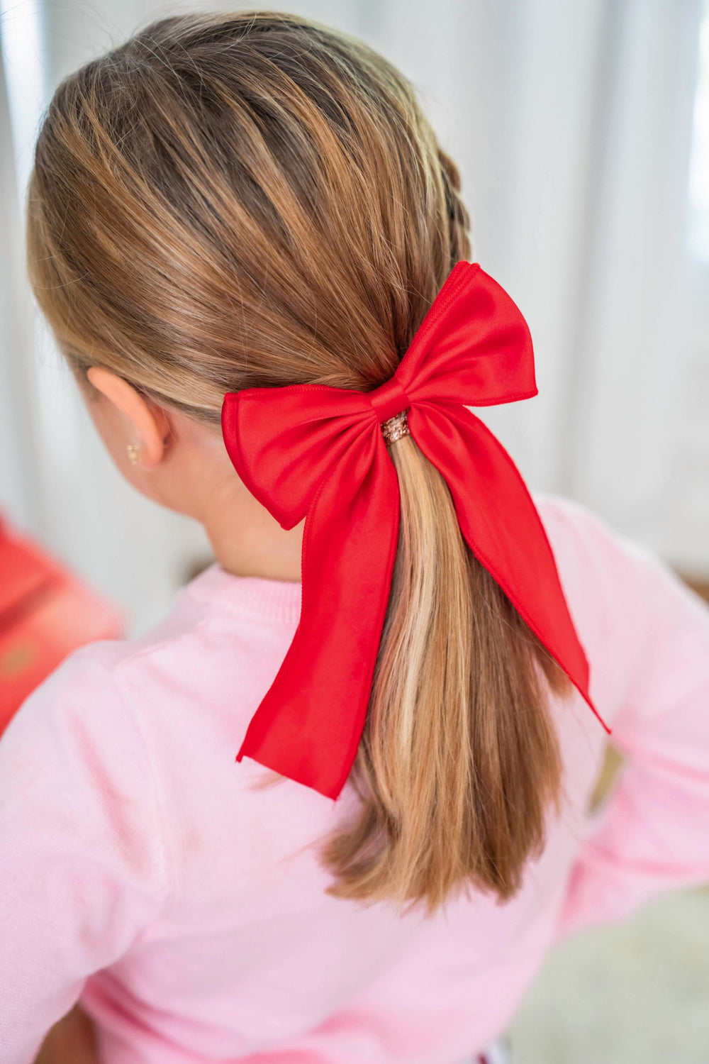 little girl in bright red oversized satin double bow for Christmas