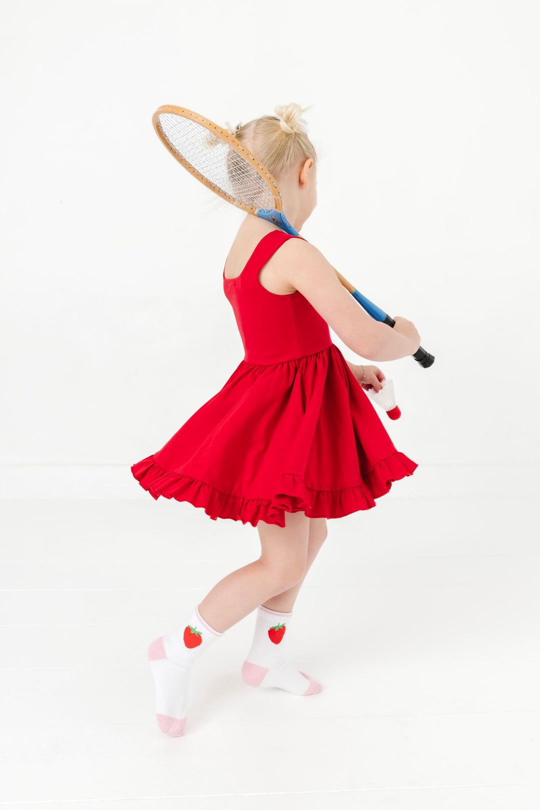 little girl twirling with racket in bright red sleeveless twirl dress paired with strawberry print crew socks