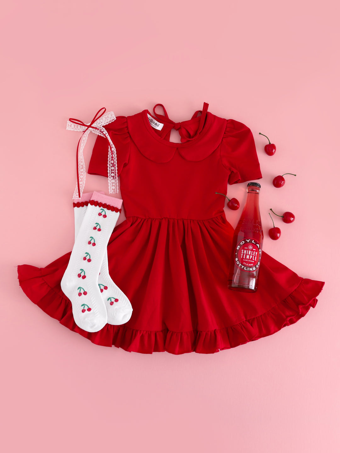 girls' outfit flat lay styled with shirly temple for bright red short sleeve twirl dress, cherry print knee socks and matching white and red lace ribbon hair bow