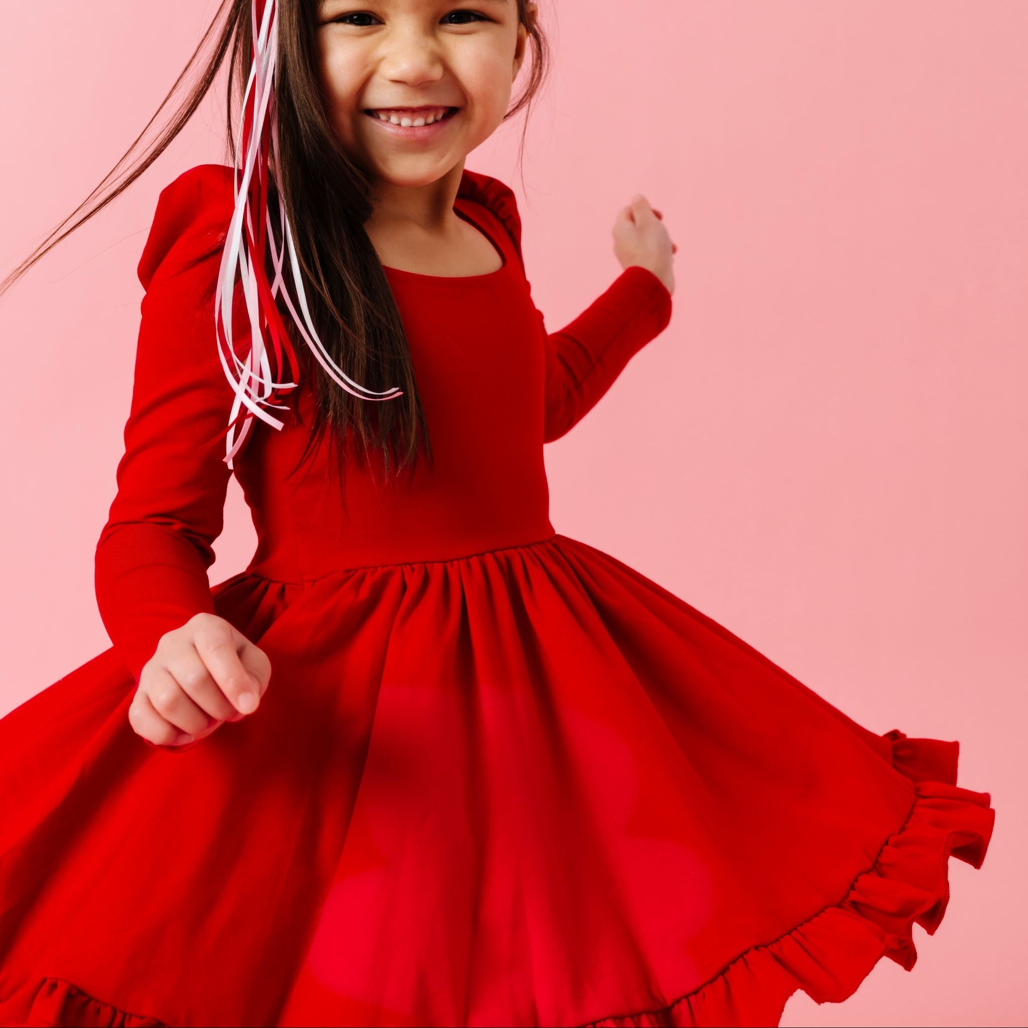 happy girl twirling in bright red twirl dress with long sleeves and square neckline for valentine's day