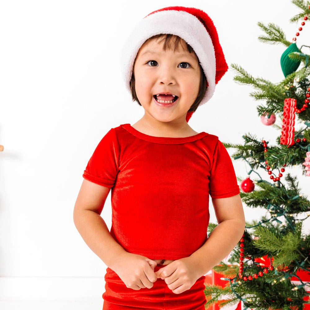 young girl in Santa hat and bright red velvet top and leggings for Christmas