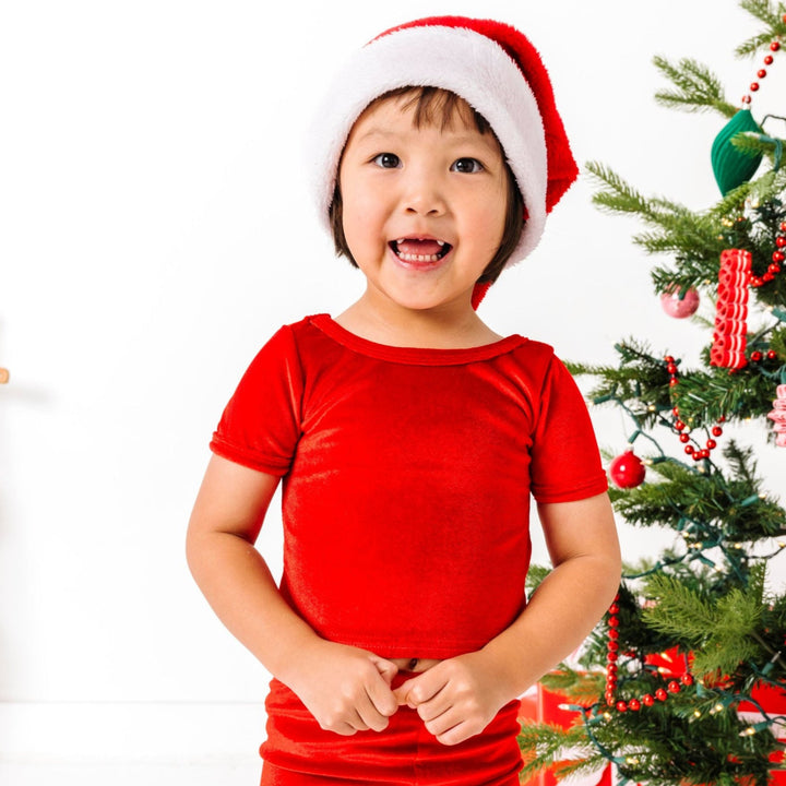 young girl in Santa hat and bright red velvet top and leggings for Christmas