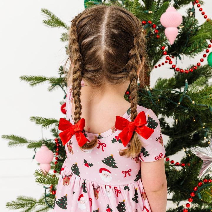 little girl in braids with bright red velvet pigtail clips paired with pink Christmas theme twirl dress