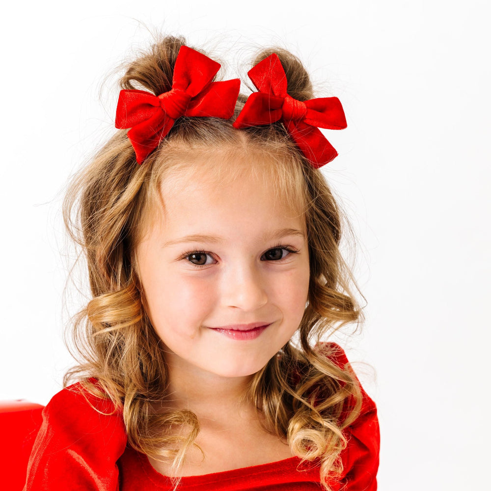 little girl in bright red velvet pigtail bows on clips pared with matching red velvet tutu dress