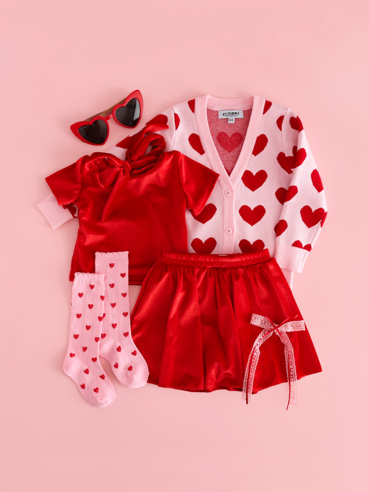 girls pink and red valentines outfit with bright red velvet top and skort paired with red and pink heart print knit cardigan and matching knee high socks