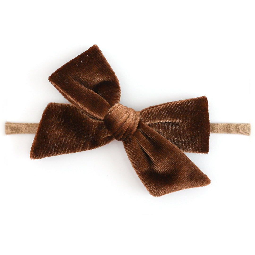 A brown velvet bow headband on a solid white background.