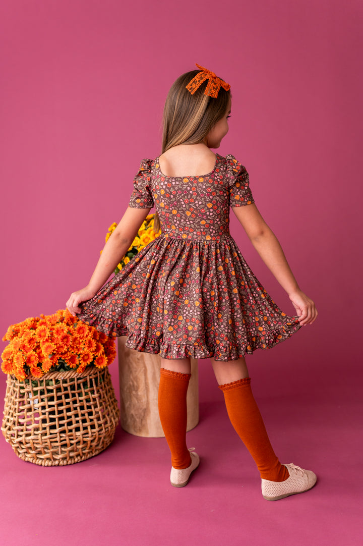 little girl in brown fall floral square neck twirl dress paired with pumpkin spice accessories