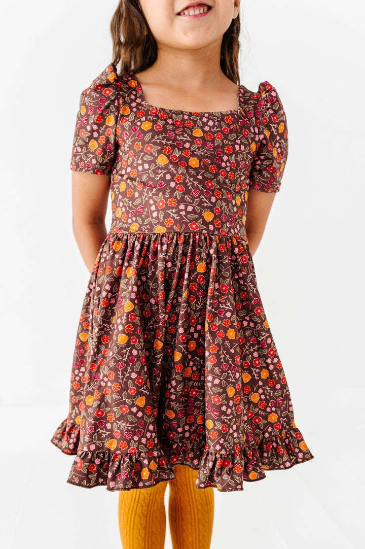 little girl in brown floral twirl dress in fall shades paired with matching mustard cable knit tights