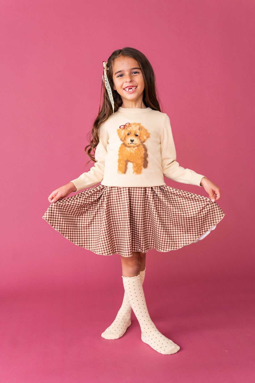 young girl wearing cream pullover sweater with puppy design paired with brown gingham twirl dress, cream dotted knee socks and matching lace hair bow