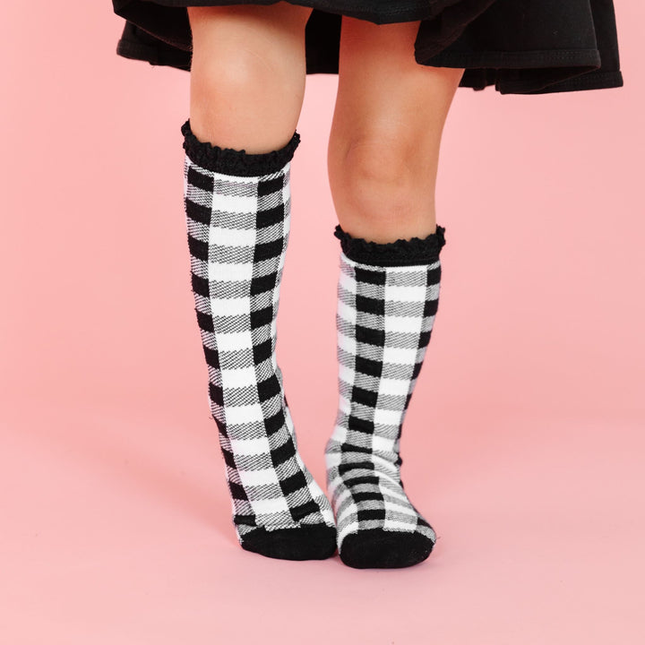 little girl in black and white buffalo print knee high socks with black lace trim