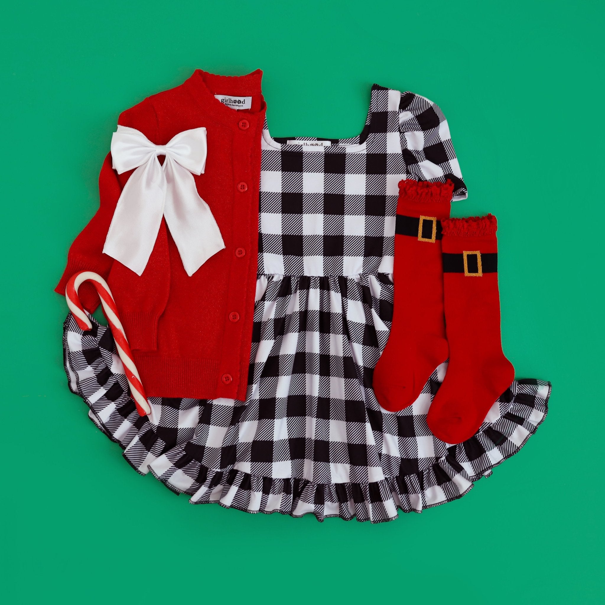 girls buffalo plaid twirl dress with Santa inspired red knee highs with buckle embellishment, sparkly red knit cardigan and white satin bow