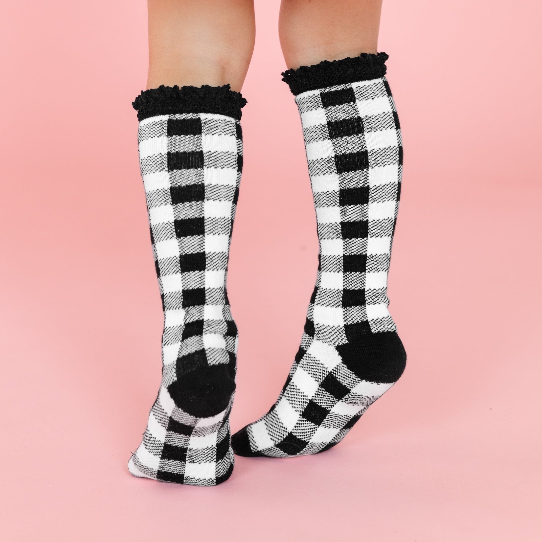 little girl in black and white buffalo print knee high socks with black lace trim