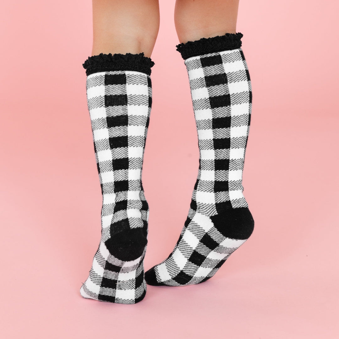 little girl in black and white buffalo print knee high socks with black lace trim
