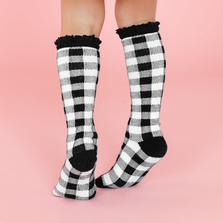 little girl in black and white buffalo print knee high socks with black lace trim