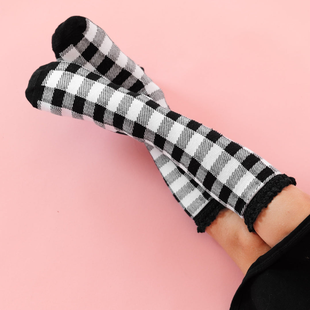 little girl in black and white buffalo print knee high socks with black lace trim and black twirl dress