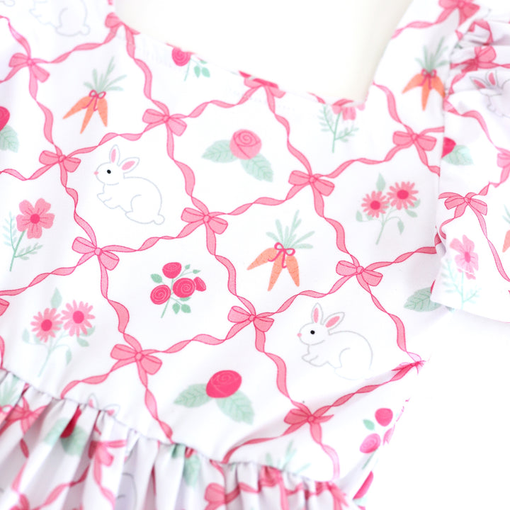 closeup of pink ribbon print with bunnies, pink spring flowers and carrots on white base for Easter