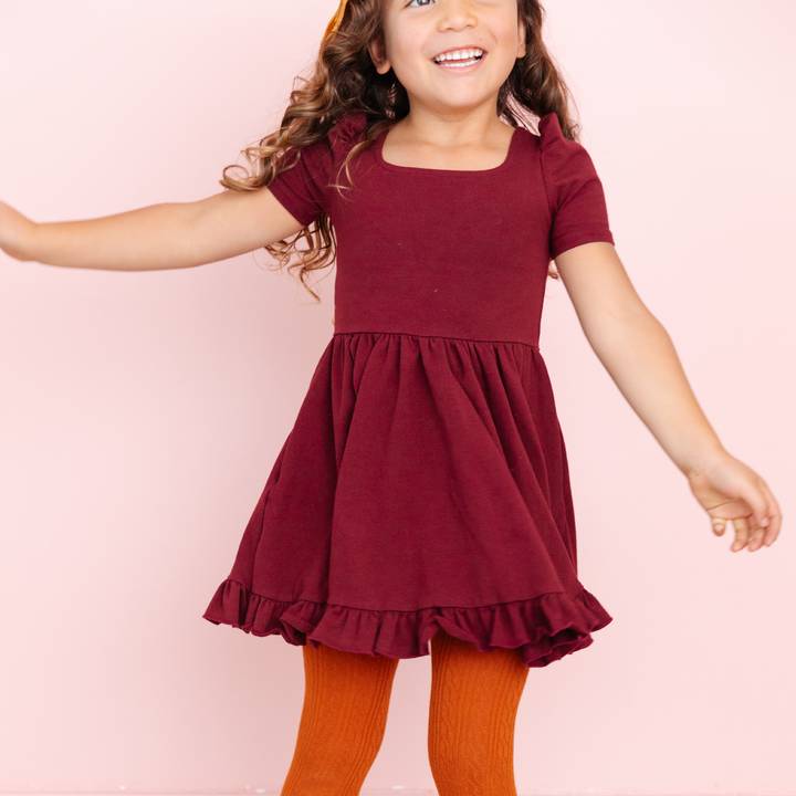 girl in burgundy square neck twirl dress and pumpkin spice tights