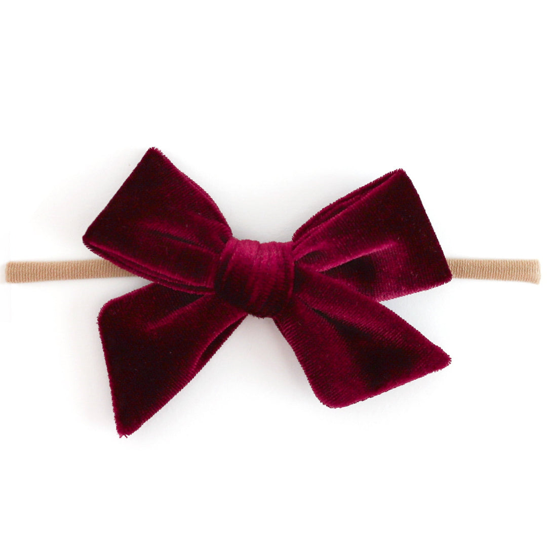 A deep burgundy velvet bow headband on a clean white background.