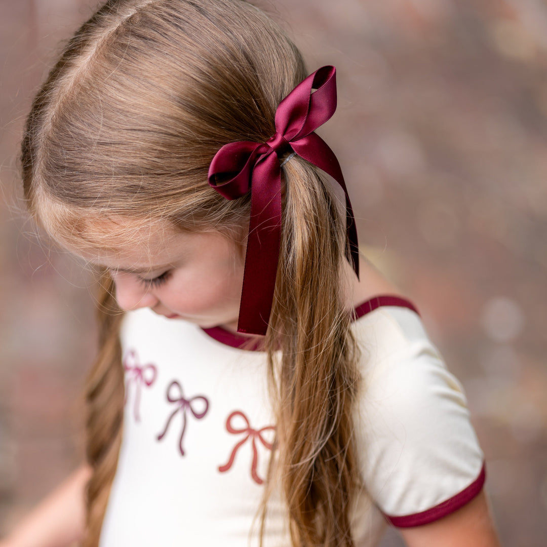 little girl in cream tee with fall bow design and matching burgundy satin ribbon bow on clip