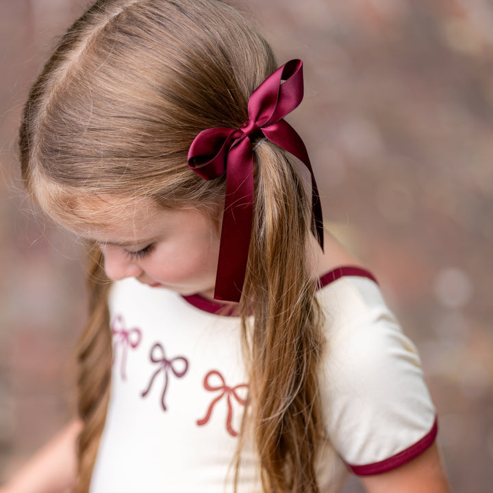 little girl in cream tee with fall bow design and matching burgundy satin ribbon bow on clip
