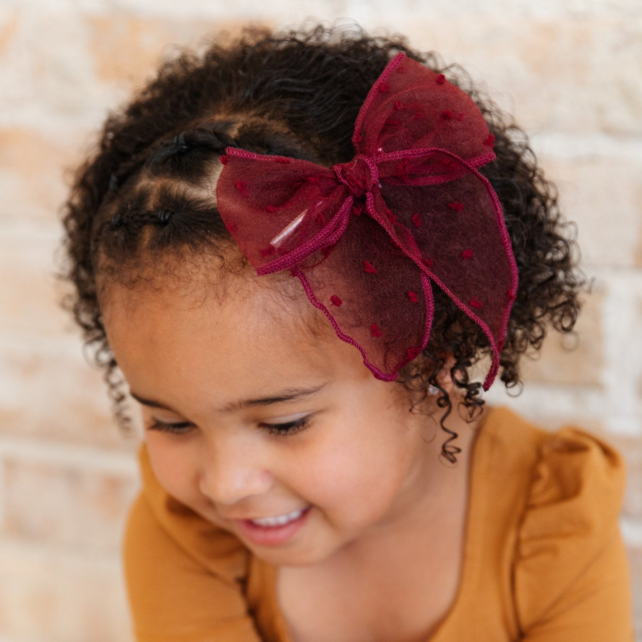 little girl in carmel colored twirl dress with sheer burgundy bow on clip