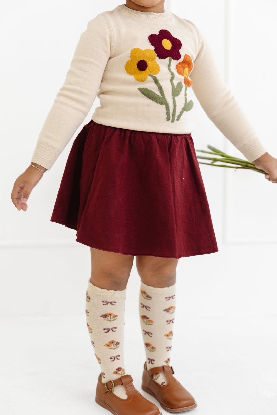 little girl in burgundy cotton blend skort and cream sweater and knee high socks with matching fall floral design