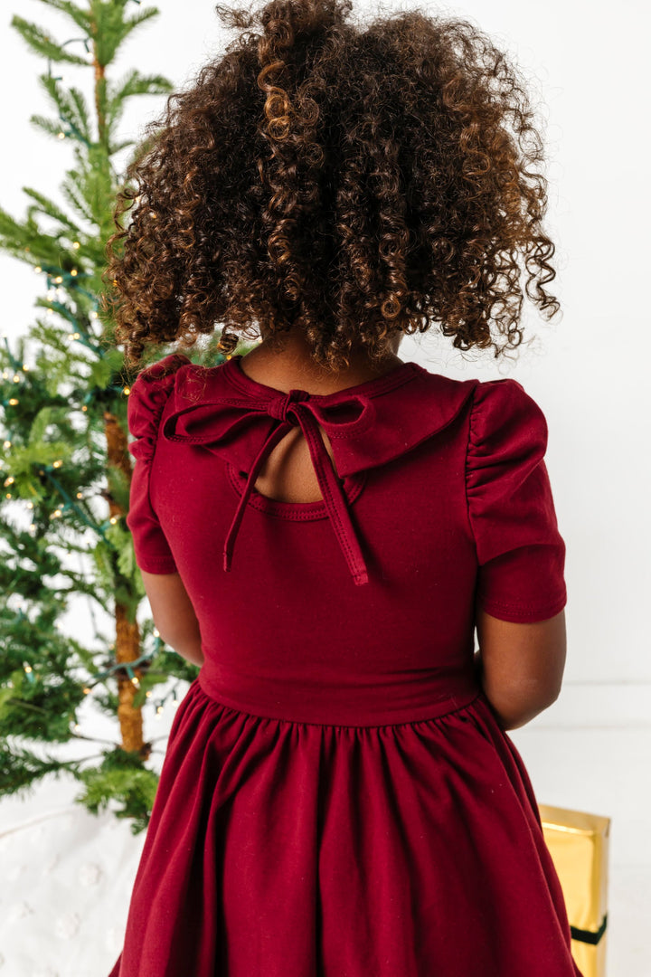 little girl in tie back, short sleeve, collared twirl dress styled for Christmas 