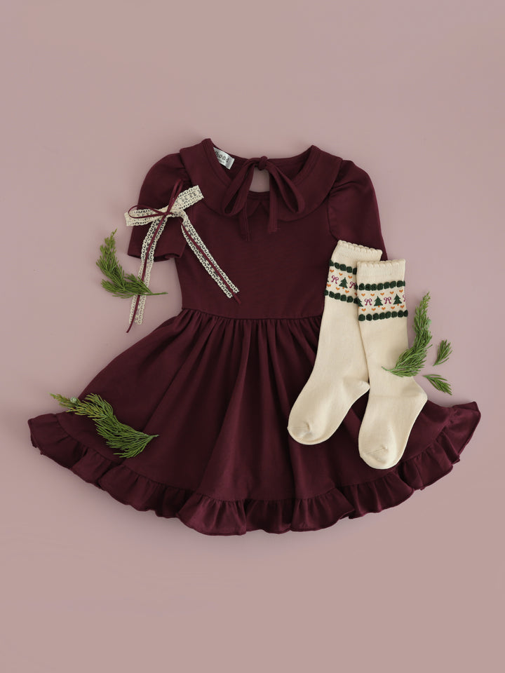 girls' Christmas flat lay with burgundy collared twirl dress paired with cream lace bow and vanilla fair isle knee socks