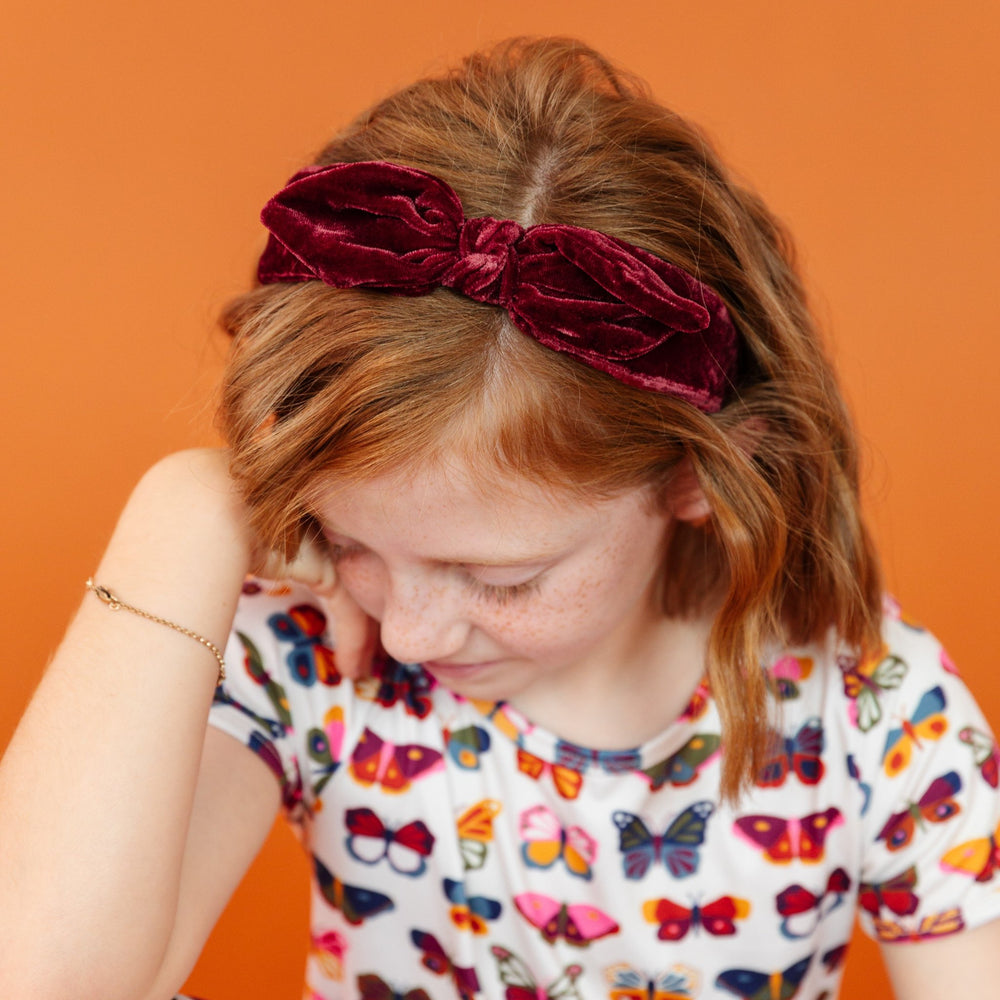 little girl in burgundy velvet headband with matching butterfly dress in fall colors