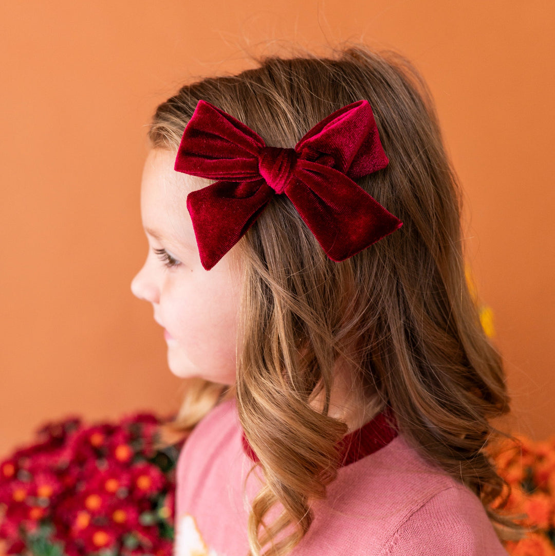 young girl wearing burgundy velvet hair bow paired with pink fall kitten sweater