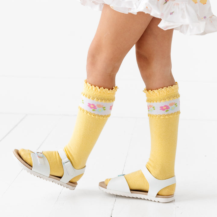 girl in yellow lace trimmed knee high socks with floral band around top