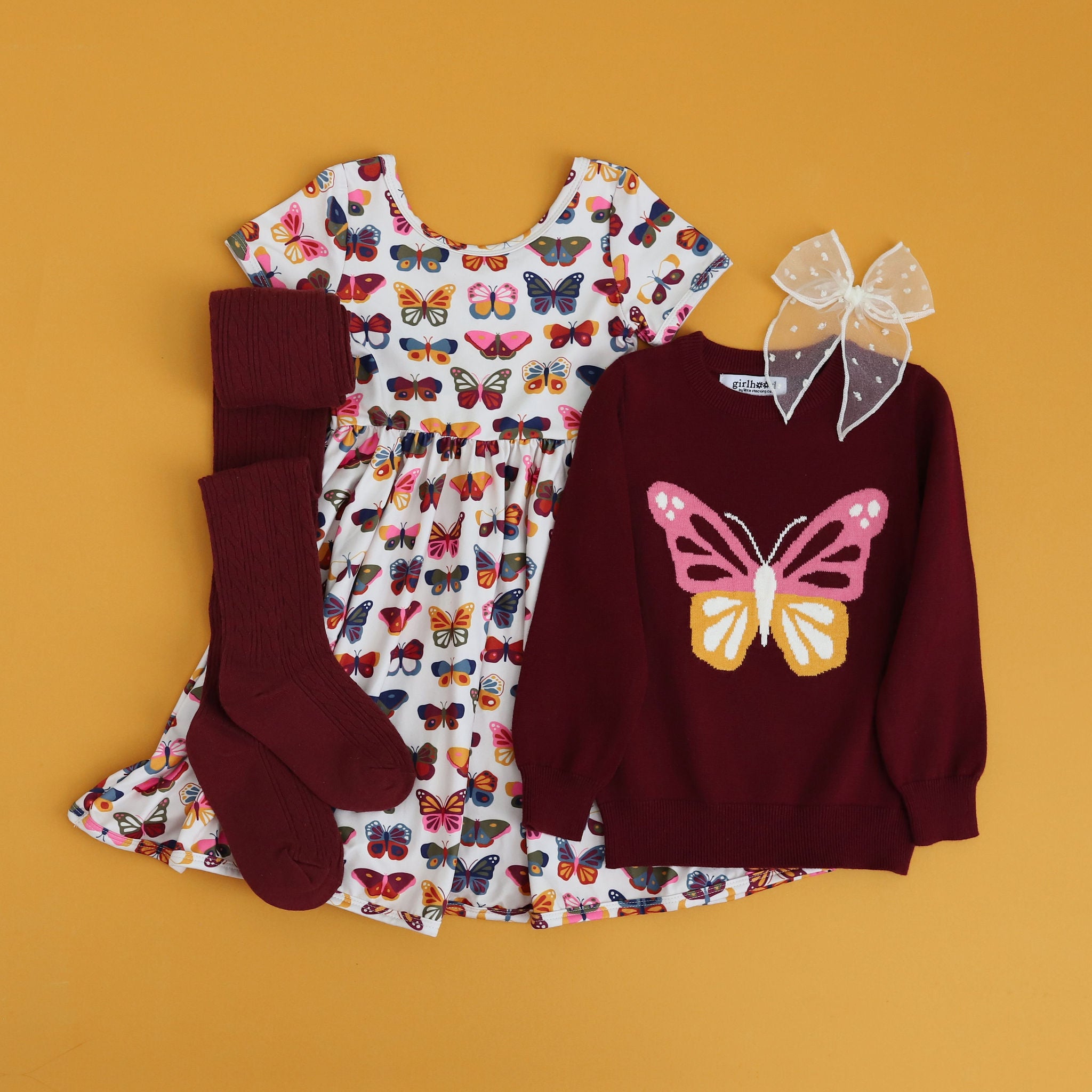 styled butterfly outfit with butterfly print dress, pullover sweater, tights and matching bow