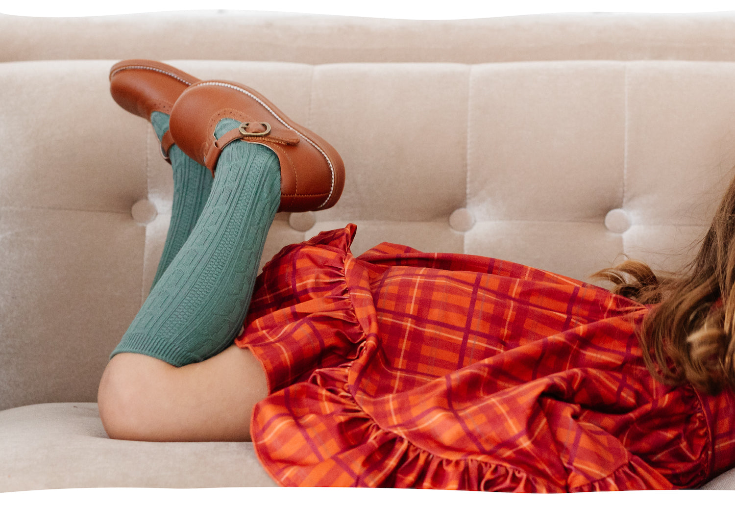 little girl wearing cable knit knee high socks and orange plaid dress
