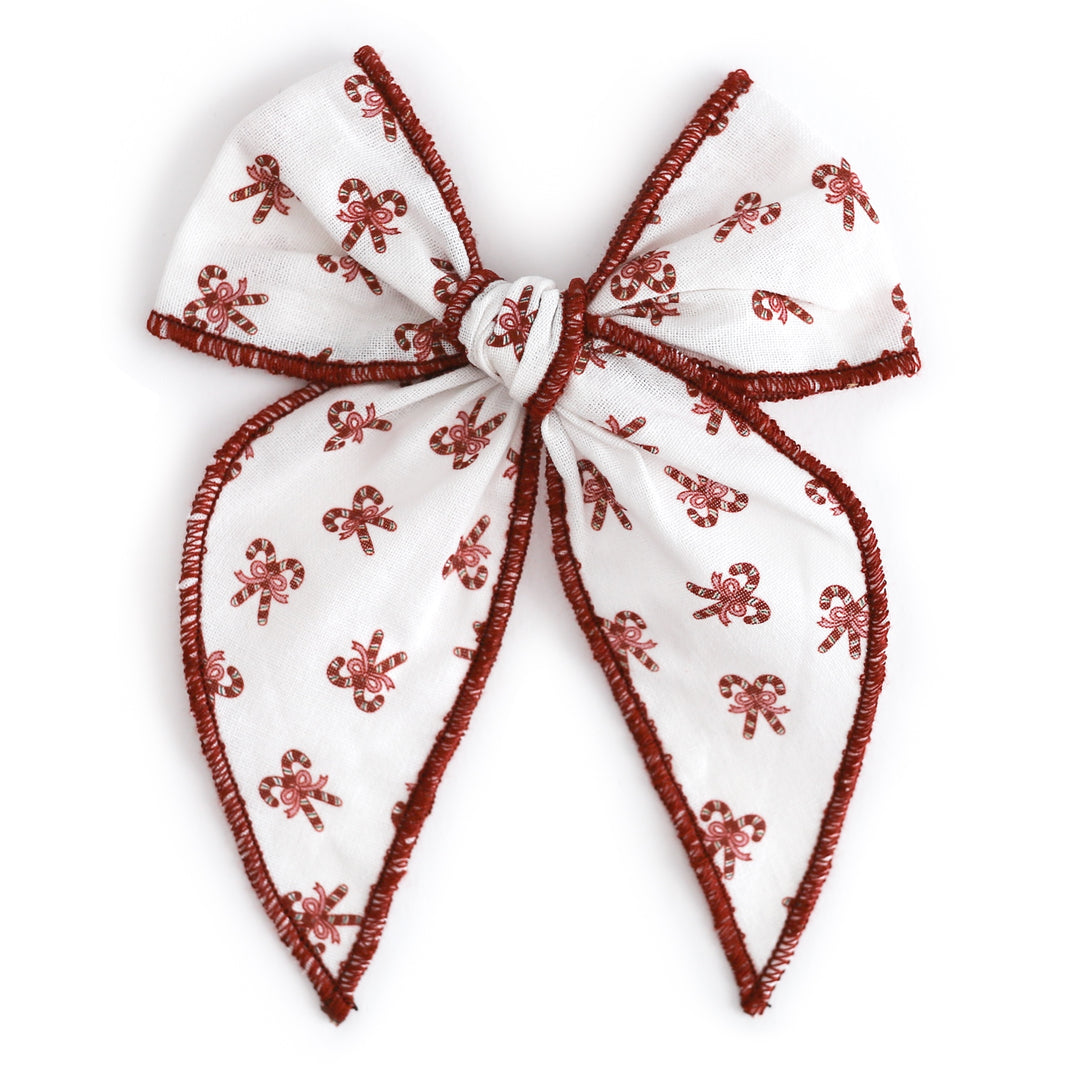 girls' white fabric bow on clip with candy cane design and red trim