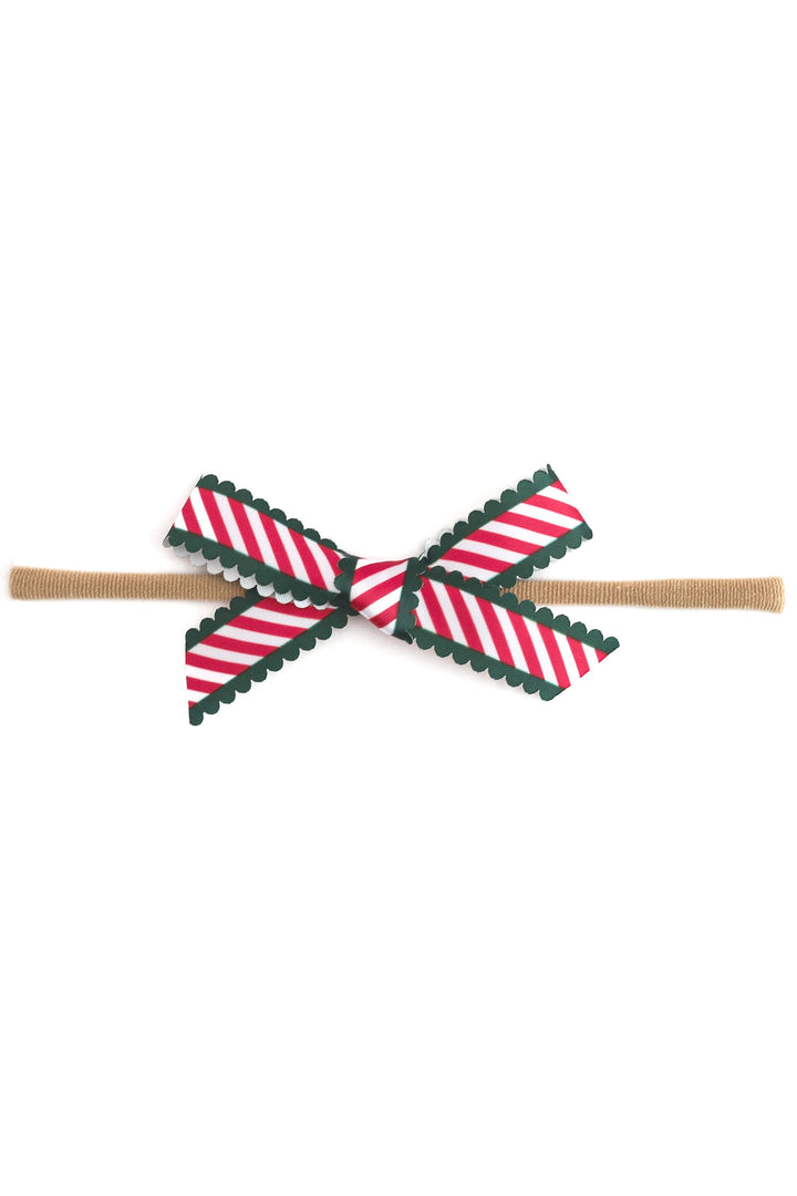photo of printed scallop ribbon baby bow in candy cane stripes with green scallop trim on nylon headband on white background