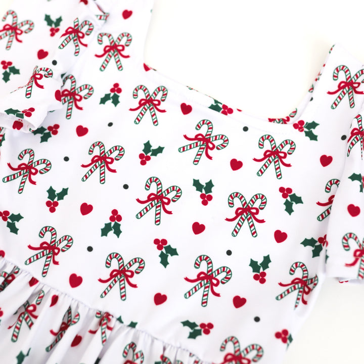 closeup of little girls classic red, white and green candy cane print dress with holly and hearts