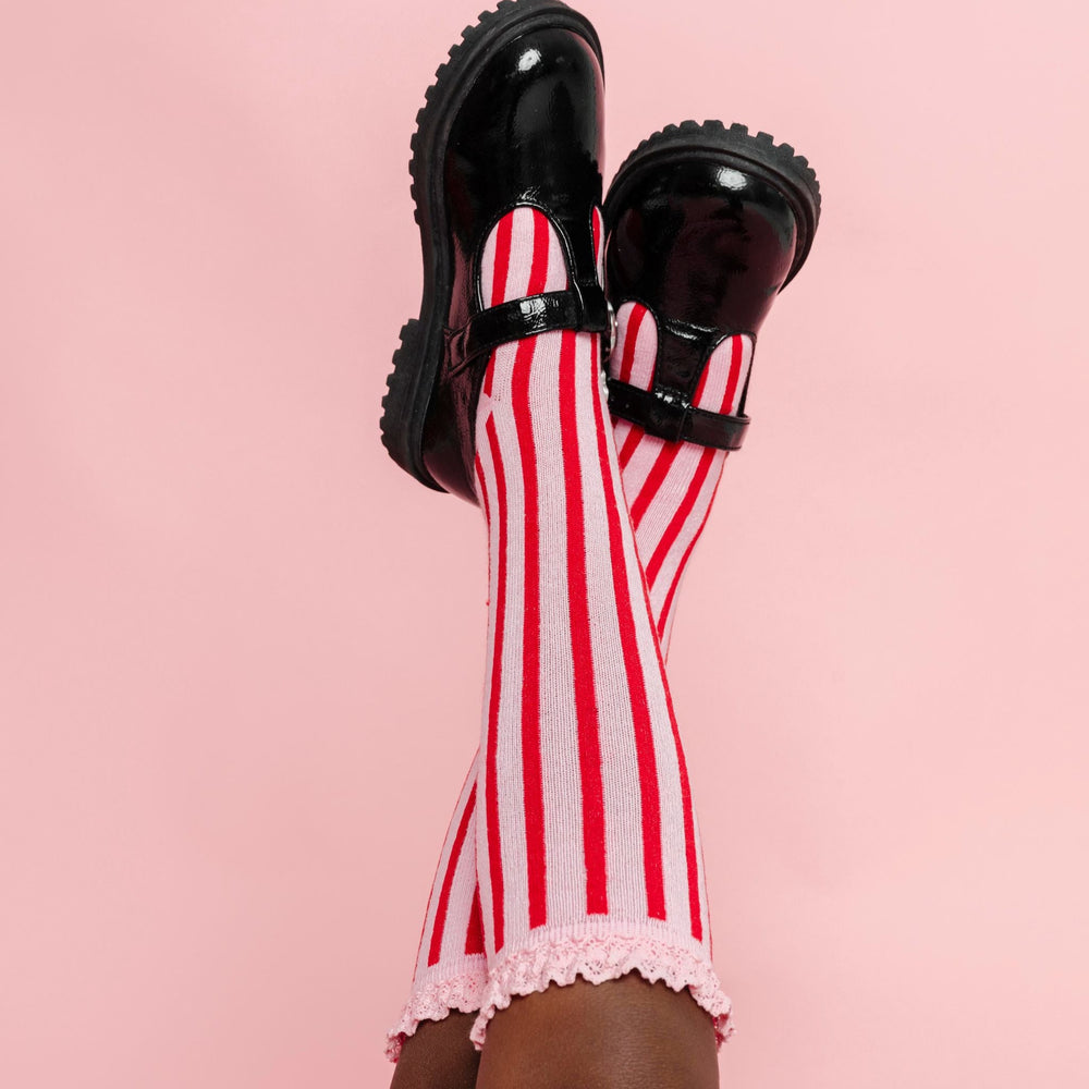 little girl wearing pink and red vertical striped knee-high socks with pink lace trim and black mary janes