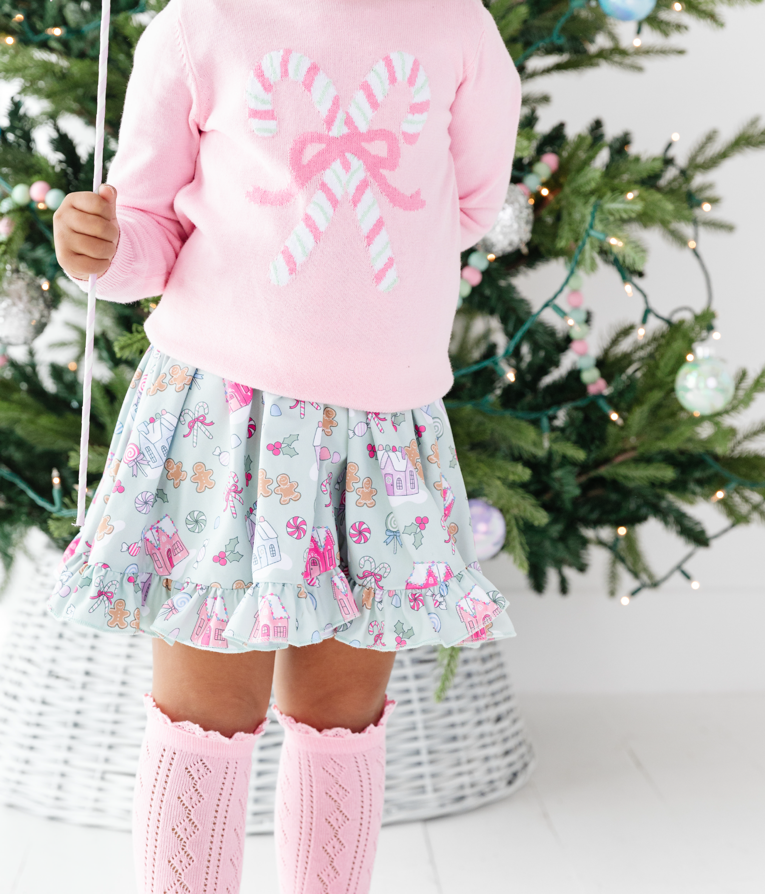 little girl in Candyland print twirl dress with matching pink candy cane pullover sweater and pink knee highs