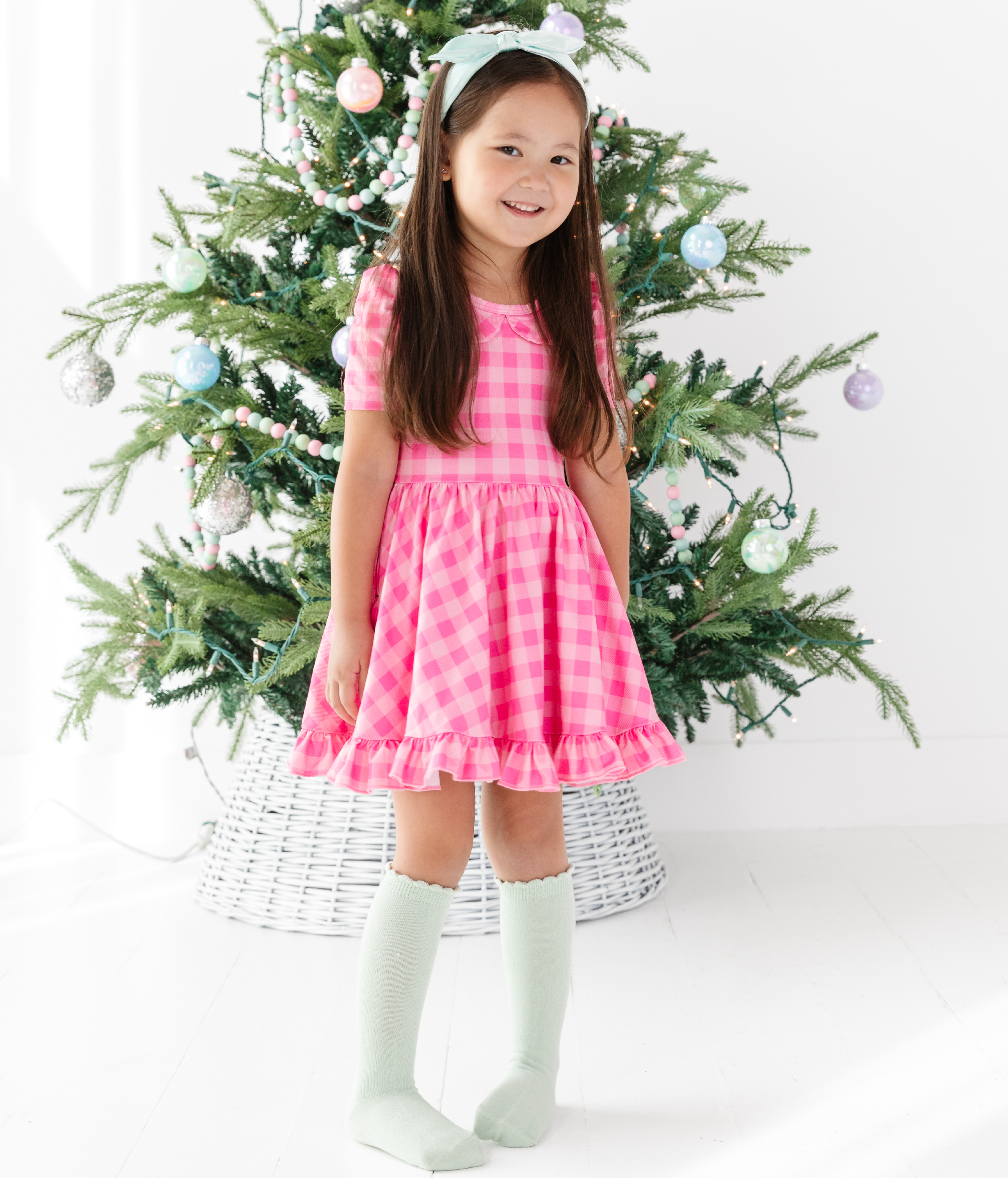 little girl in two tone pink gingham party dress with matching mint headband and knee-high socks