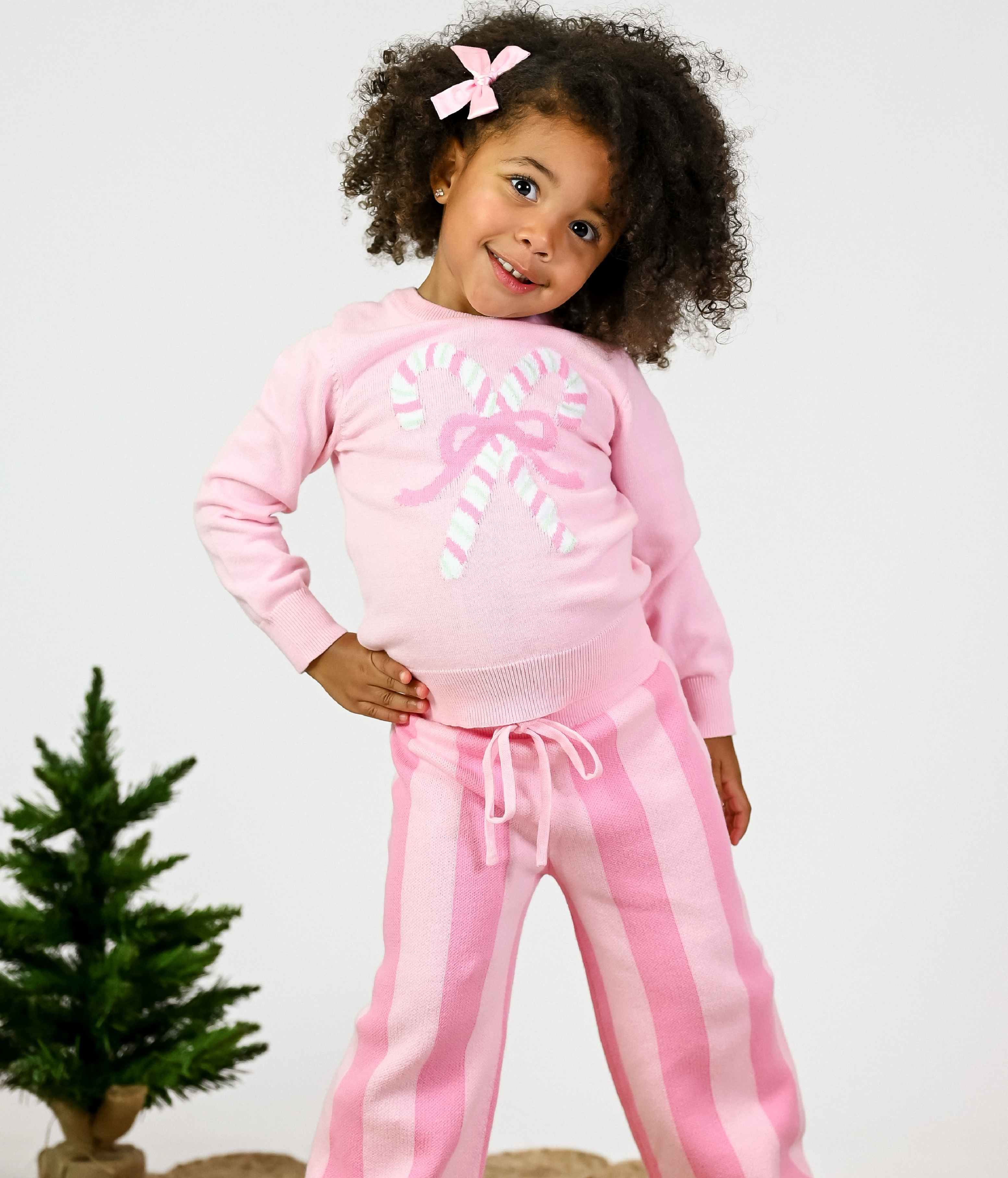 little girl in pullover sweater with pastel pink candy canes and matching two tone pink striped sweater pants