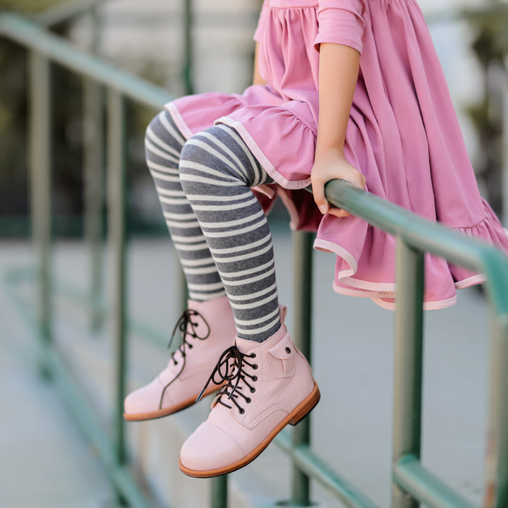 little girl sitting on bar wearing charcoal striped pattern tights and cute pink leather boots